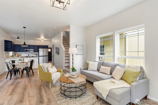 living room featuring light wood-type flooring, stairway, and baseboards