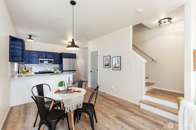 dining area featuring light wood-style flooring, stairway, and baseboards