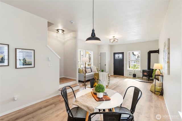 dining room featuring light wood-type flooring, a wood stove, and baseboards