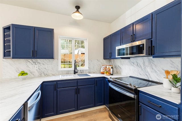 kitchen featuring stainless steel appliances, decorative backsplash, a sink, and blue cabinets