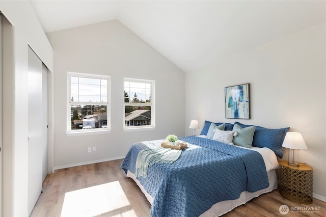 bedroom featuring light wood-type flooring, baseboards, and vaulted ceiling