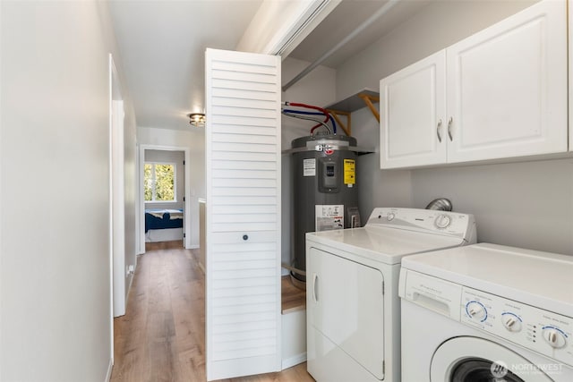 laundry room featuring cabinet space, separate washer and dryer, light wood-style floors, and electric water heater