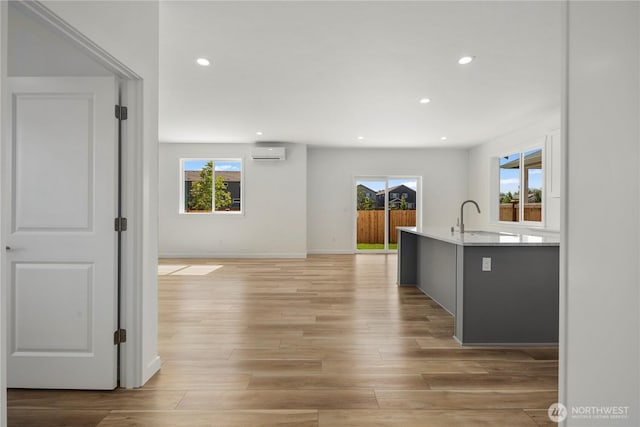 kitchen with light wood finished floors, recessed lighting, light countertops, an AC wall unit, and a sink