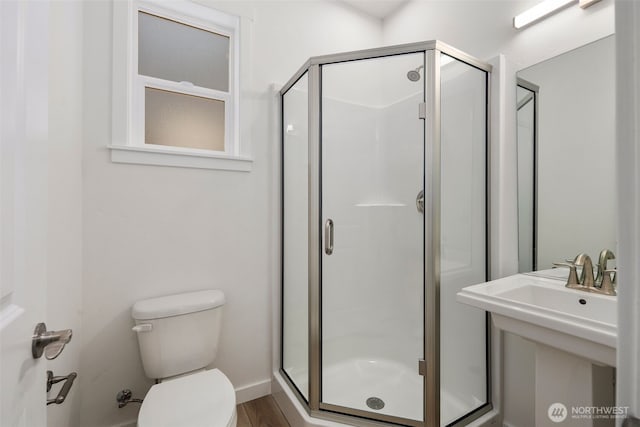 bathroom featuring toilet, a shower stall, and wood finished floors