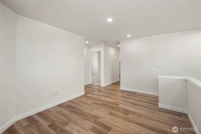 empty room featuring recessed lighting, light wood-type flooring, and baseboards