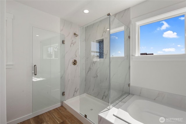 bathroom with recessed lighting, a garden tub, a marble finish shower, and wood finished floors