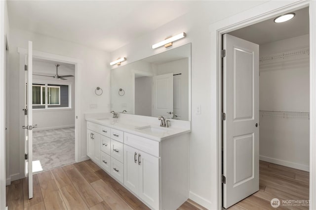 bathroom with double vanity, a spacious closet, a sink, and wood finished floors