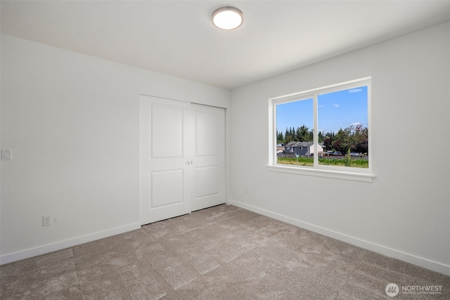 unfurnished bedroom with carpet floors, a closet, and baseboards