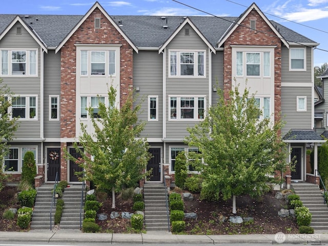 townhome / multi-family property featuring brick siding and roof with shingles