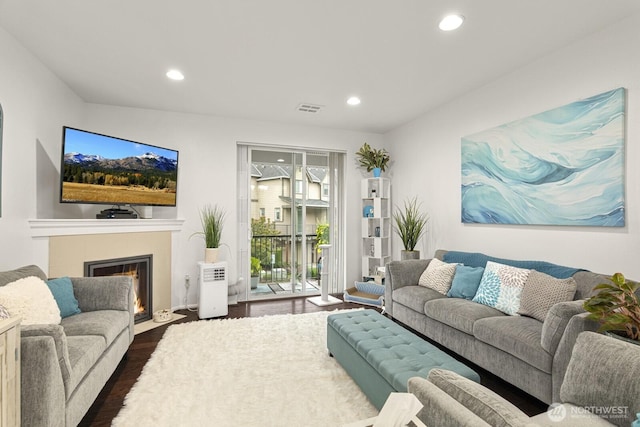 living area with dark wood-type flooring, recessed lighting, visible vents, and a fireplace with flush hearth