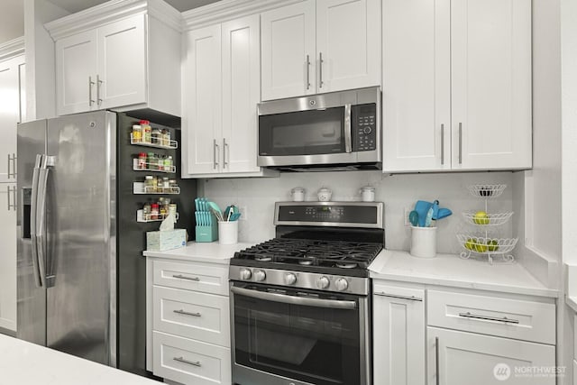 kitchen with stainless steel appliances, backsplash, and white cabinetry