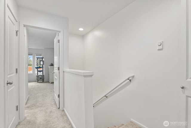 hall with recessed lighting, baseboards, light carpet, and an upstairs landing