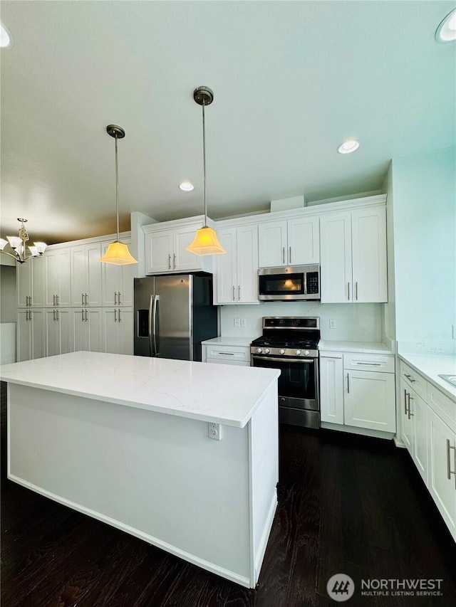 kitchen with light countertops, appliances with stainless steel finishes, white cabinets, and a center island