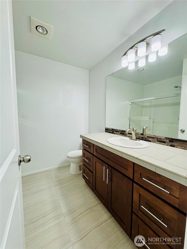 full bath featuring tile patterned flooring, toilet, vanity, baseboards, and a shower stall