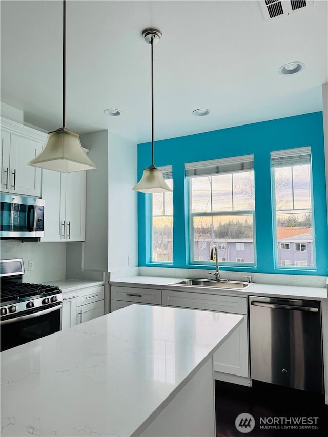 kitchen featuring appliances with stainless steel finishes, white cabinets, visible vents, and a sink