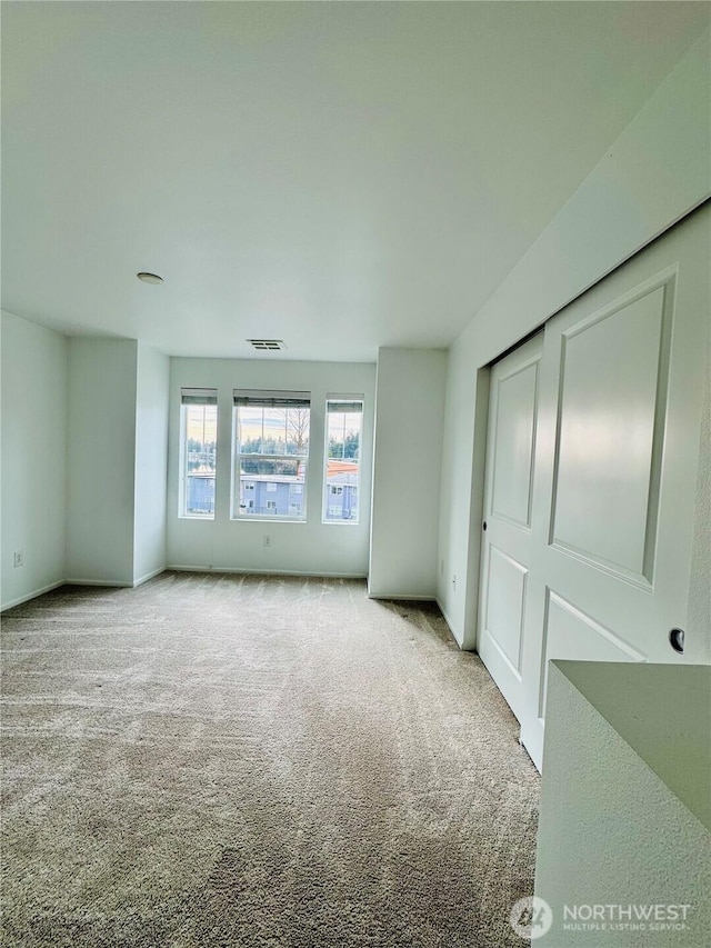 unfurnished bedroom with a closet, carpet flooring, visible vents, and baseboards