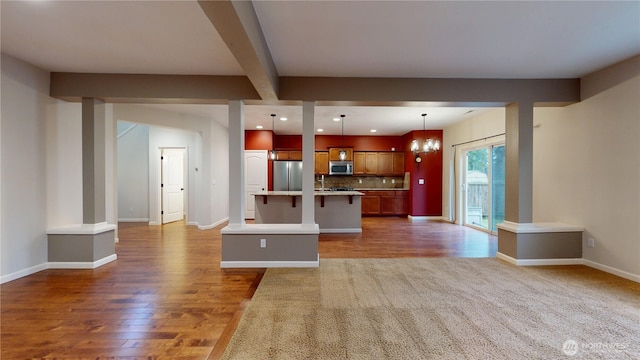 kitchen with baseboards, decorative backsplash, appliances with stainless steel finishes, open floor plan, and wood finished floors