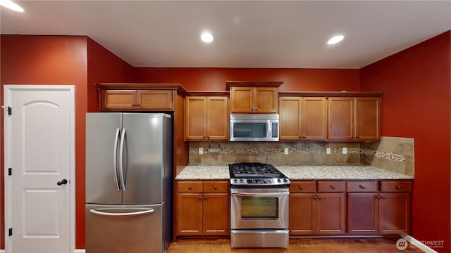 kitchen featuring appliances with stainless steel finishes, brown cabinets, and backsplash