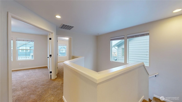 hallway featuring recessed lighting, baseboards, light colored carpet, and an upstairs landing