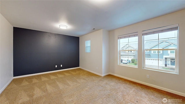 unfurnished room with visible vents, baseboards, and light colored carpet