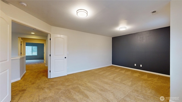 unfurnished room with carpet, visible vents, and baseboards