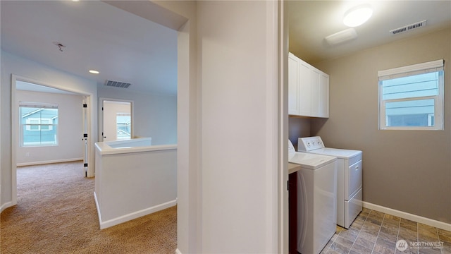 washroom with cabinet space, baseboards, visible vents, and washing machine and clothes dryer