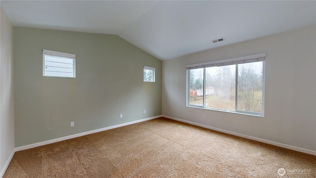 carpeted spare room with a healthy amount of sunlight, baseboards, visible vents, and vaulted ceiling