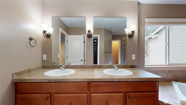 bathroom with a relaxing tiled tub, a sink, and double vanity