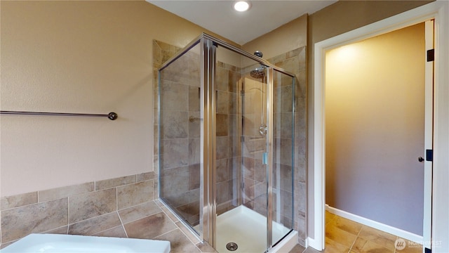 full bathroom featuring a shower stall, baseboards, and tile patterned floors