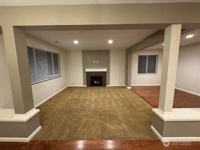 unfurnished living room with recessed lighting, a fireplace, wood finished floors, and baseboards