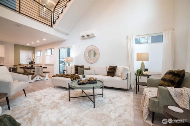 living room with light wood-style flooring, a wall mounted AC, a towering ceiling, and recessed lighting