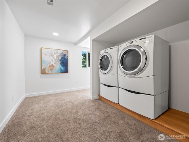 clothes washing area with carpet floors, washer and dryer, laundry area, and baseboards