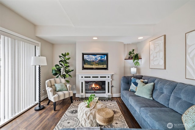 living room featuring a glass covered fireplace, recessed lighting, baseboards, and dark wood-style flooring