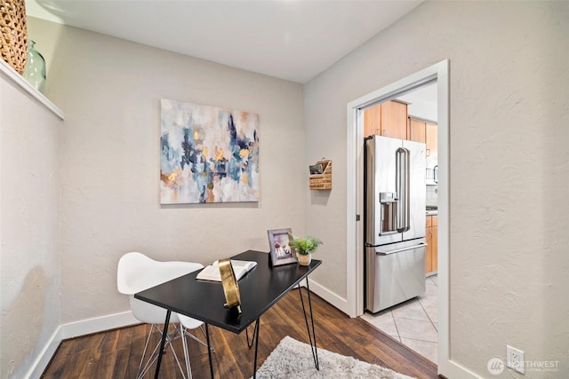 office space with light wood-style floors, baseboards, and a textured wall