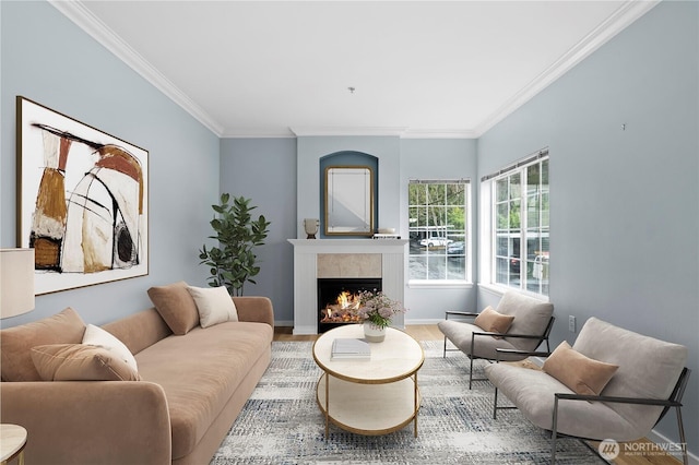 living area featuring crown molding, a lit fireplace, baseboards, and wood finished floors