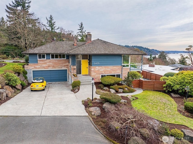 view of front of home with a garage, stone siding, driveway, and fence