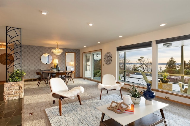 living area with recessed lighting, an accent wall, baseboards, wallpapered walls, and an inviting chandelier