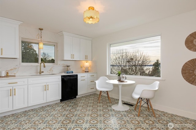 kitchen featuring tasteful backsplash, white cabinets, dishwasher, light countertops, and a sink