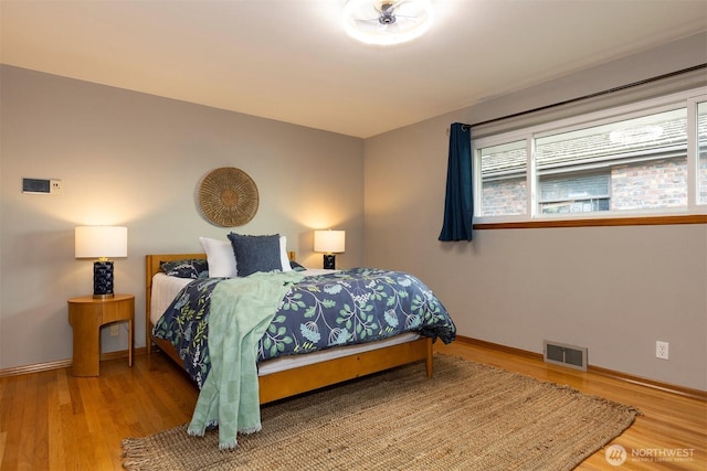 bedroom featuring wood finished floors, visible vents, and baseboards