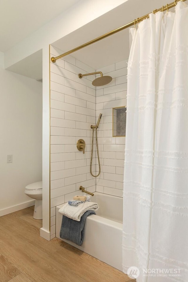 bathroom with shower / tub combo with curtain, wood finished floors, toilet, and baseboards