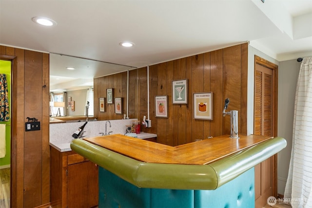 bar with wood walls, indoor wet bar, and recessed lighting