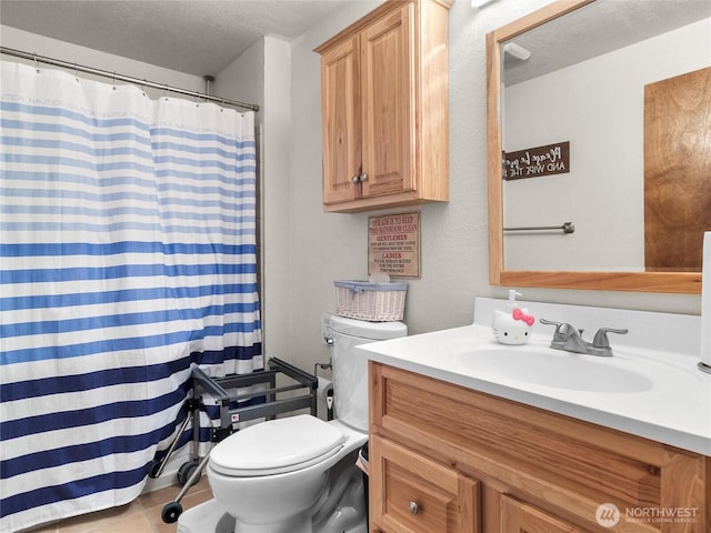 bathroom with a textured ceiling, vanity, toilet, and tile patterned floors