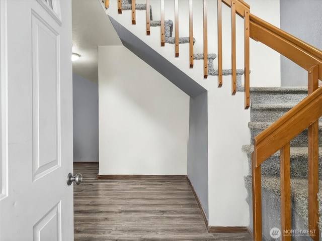 staircase featuring wood finished floors and baseboards