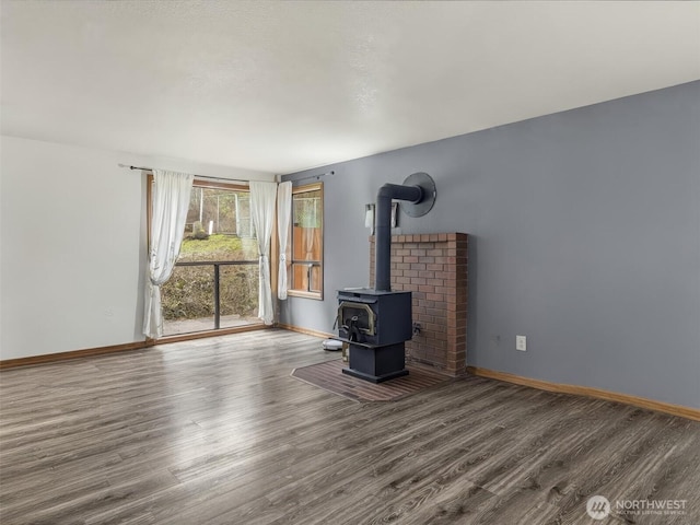 unfurnished living room with a wood stove, baseboards, and dark wood-style flooring