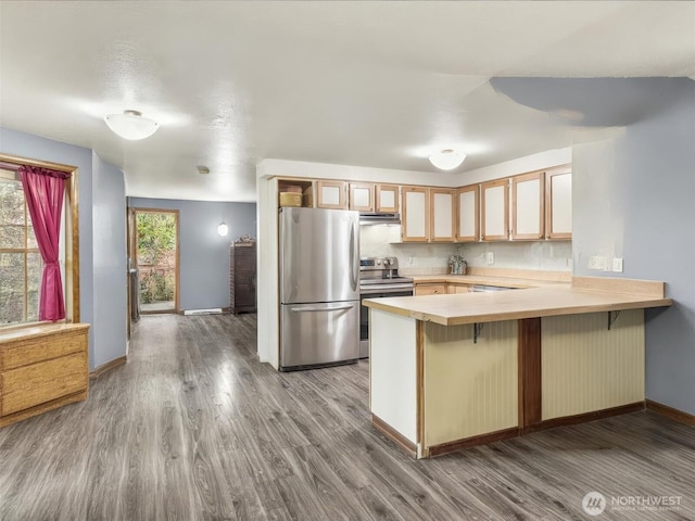 kitchen featuring stainless steel appliances, light countertops, a peninsula, and a breakfast bar area