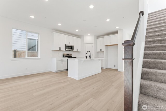 9701 205th St E Unit 28, Graham, WA 98338 - kitchen featuring stainless steel microwave, a sink, light wood-style flooring, recessed lighting, and white cabinets