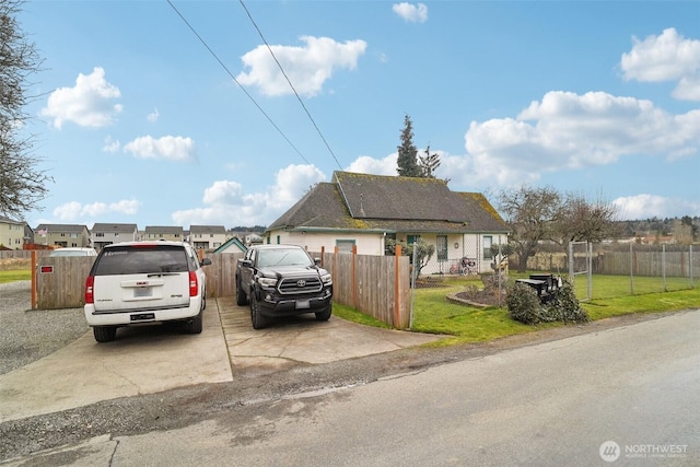 view of front facade with a fenced front yard, roof mounted solar panels, and a front lawn