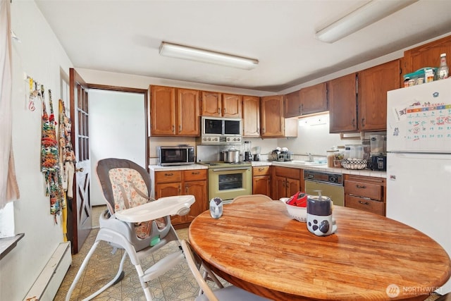 kitchen featuring white appliances, brown cabinetry, a baseboard radiator, light countertops, and a sink