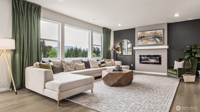 living area with a glass covered fireplace, baseboards, and light wood finished floors