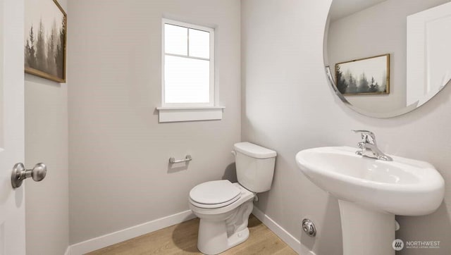 bathroom featuring toilet, baseboards, and wood finished floors